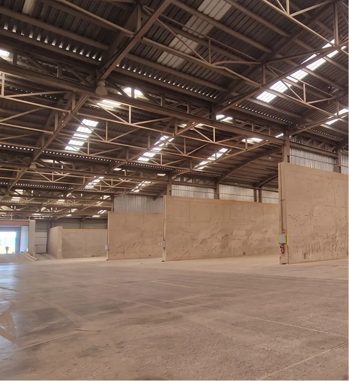 Inside a covered storage warehouse, with concrete bays under a steel roof.